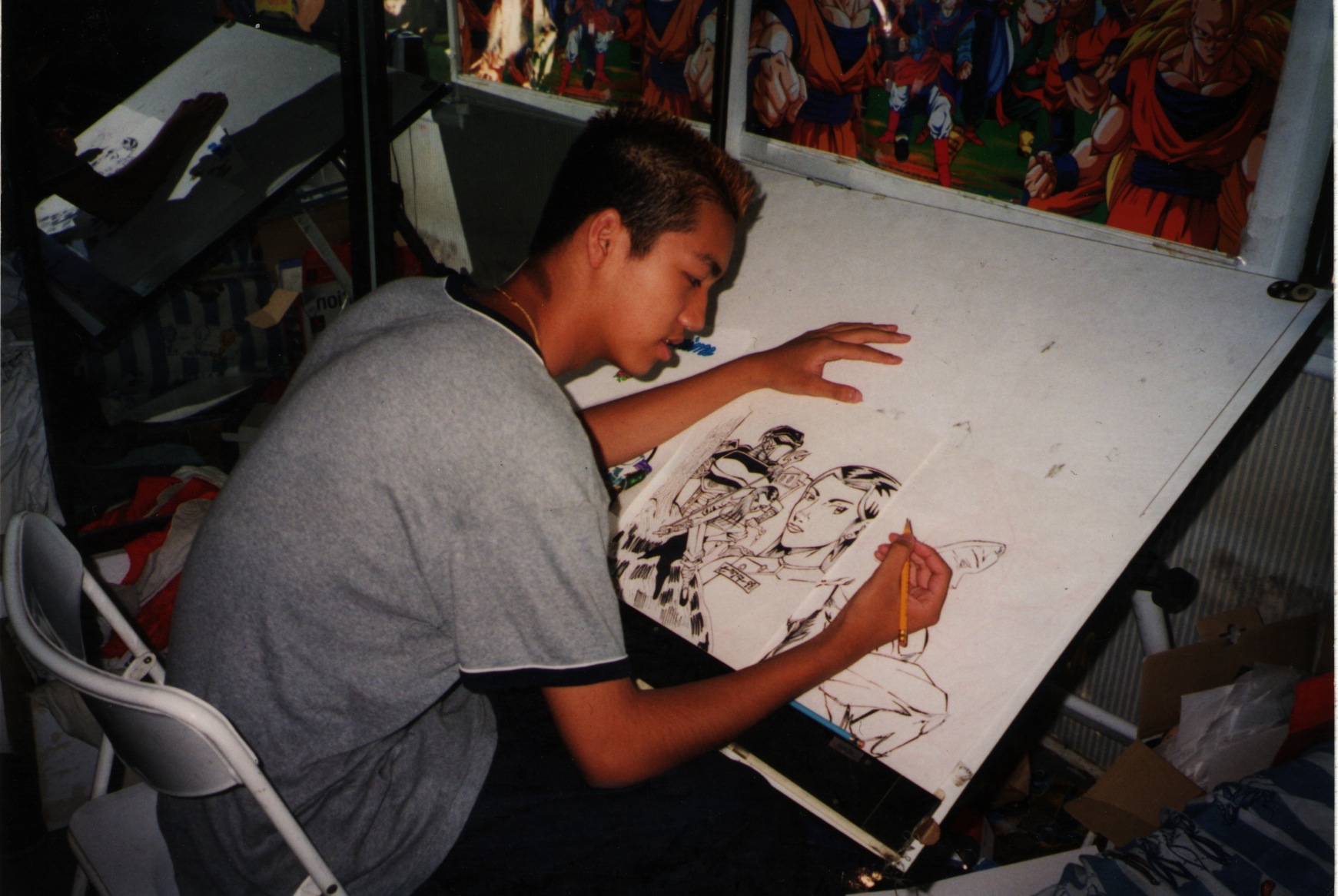 Teenage Vic drawing comic art at a drafting table