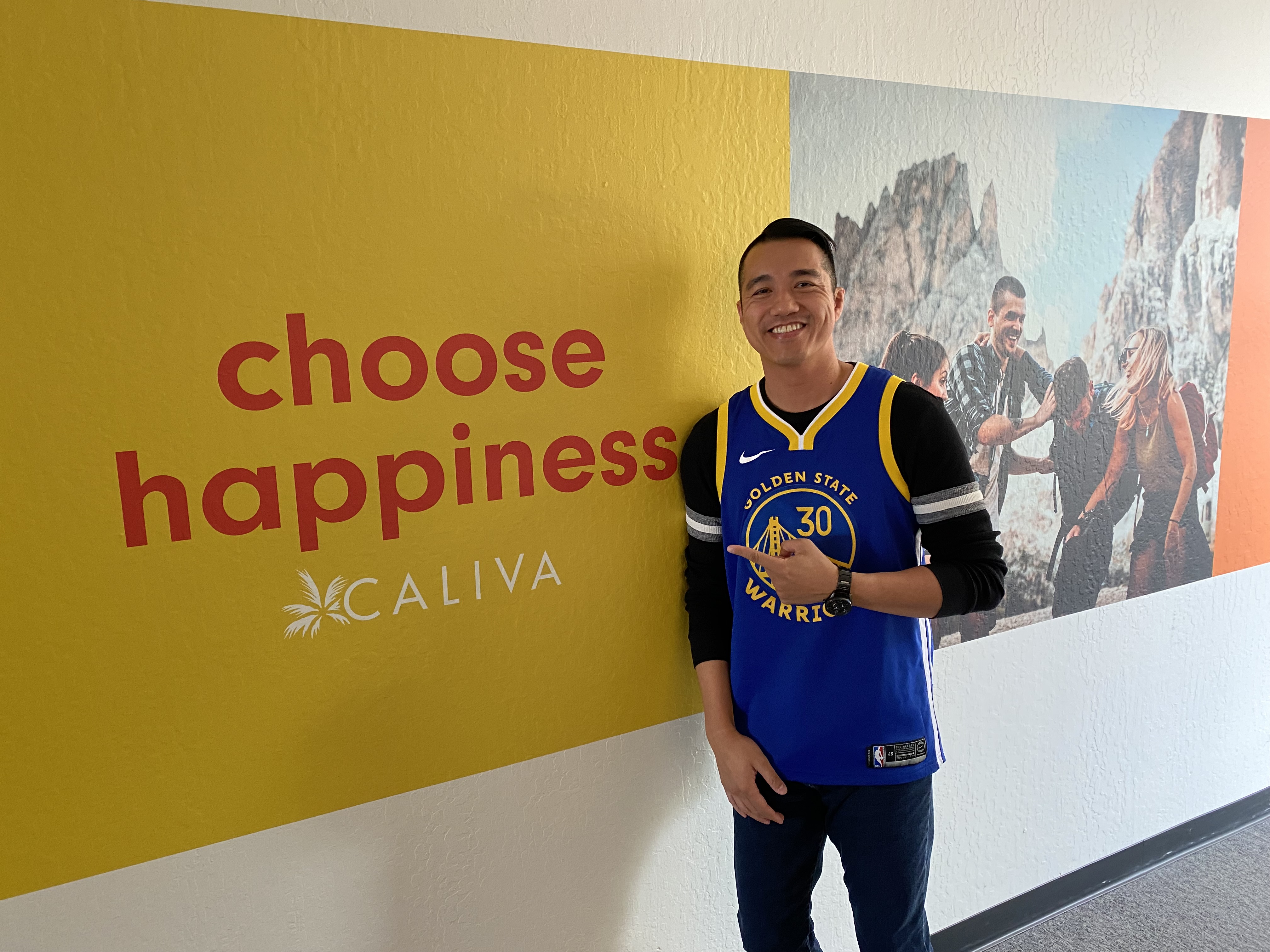 Vic smiling in front of a Choose Happiness wall at Caliva